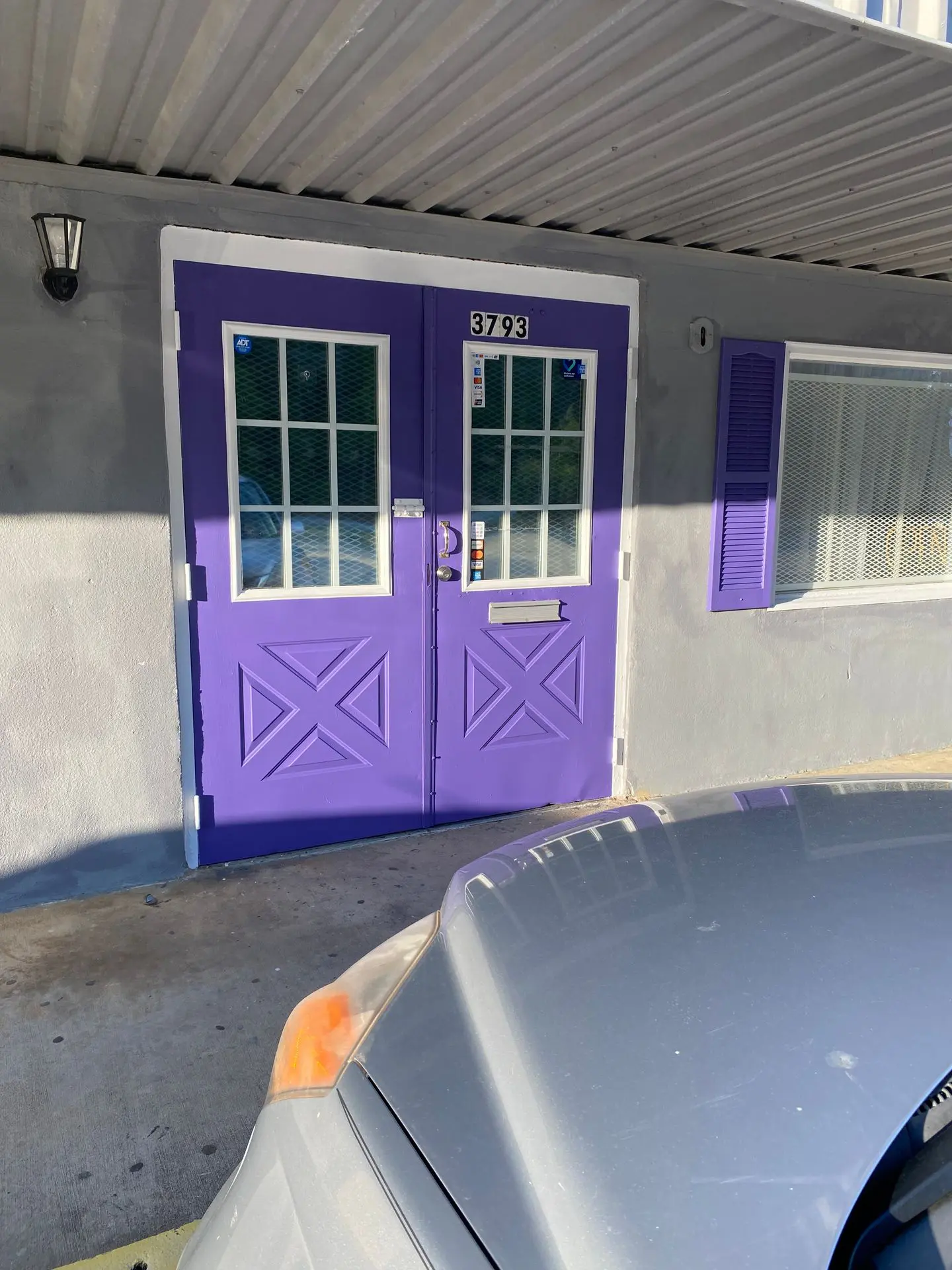 A purple door and window in front of a building.